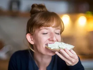 Mujer comiendo una tostada con queso fresco