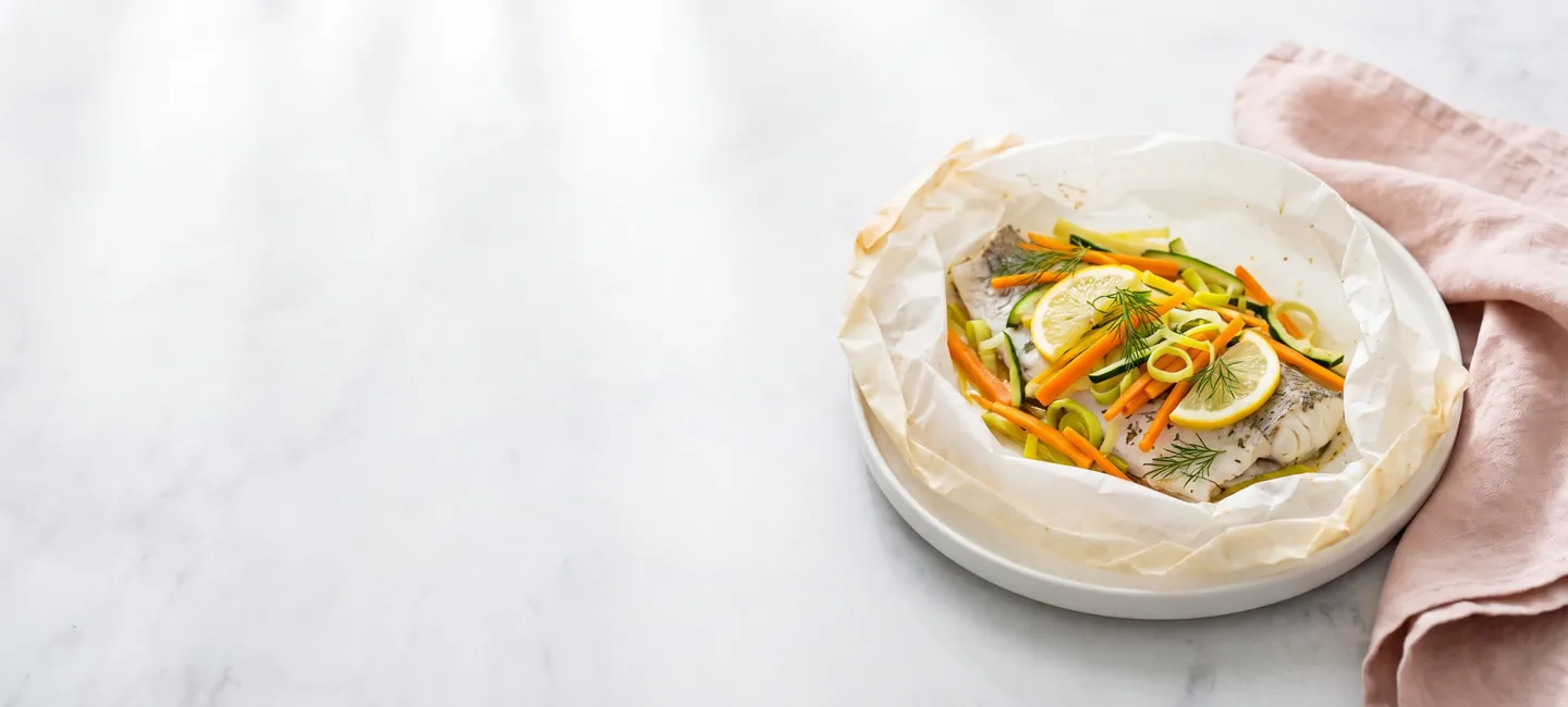 Merluza en papillote con verduras en juliana, limón y eneldo, una comida ligera y baja en grasa